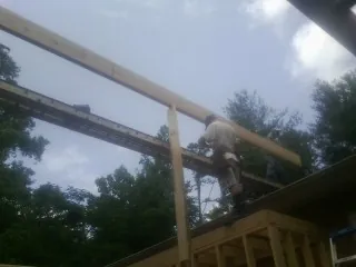 Carpenter setting a ridge beam over a new addition frame — Ice Dam Removal by Roofing Brothers in Ogdensburg