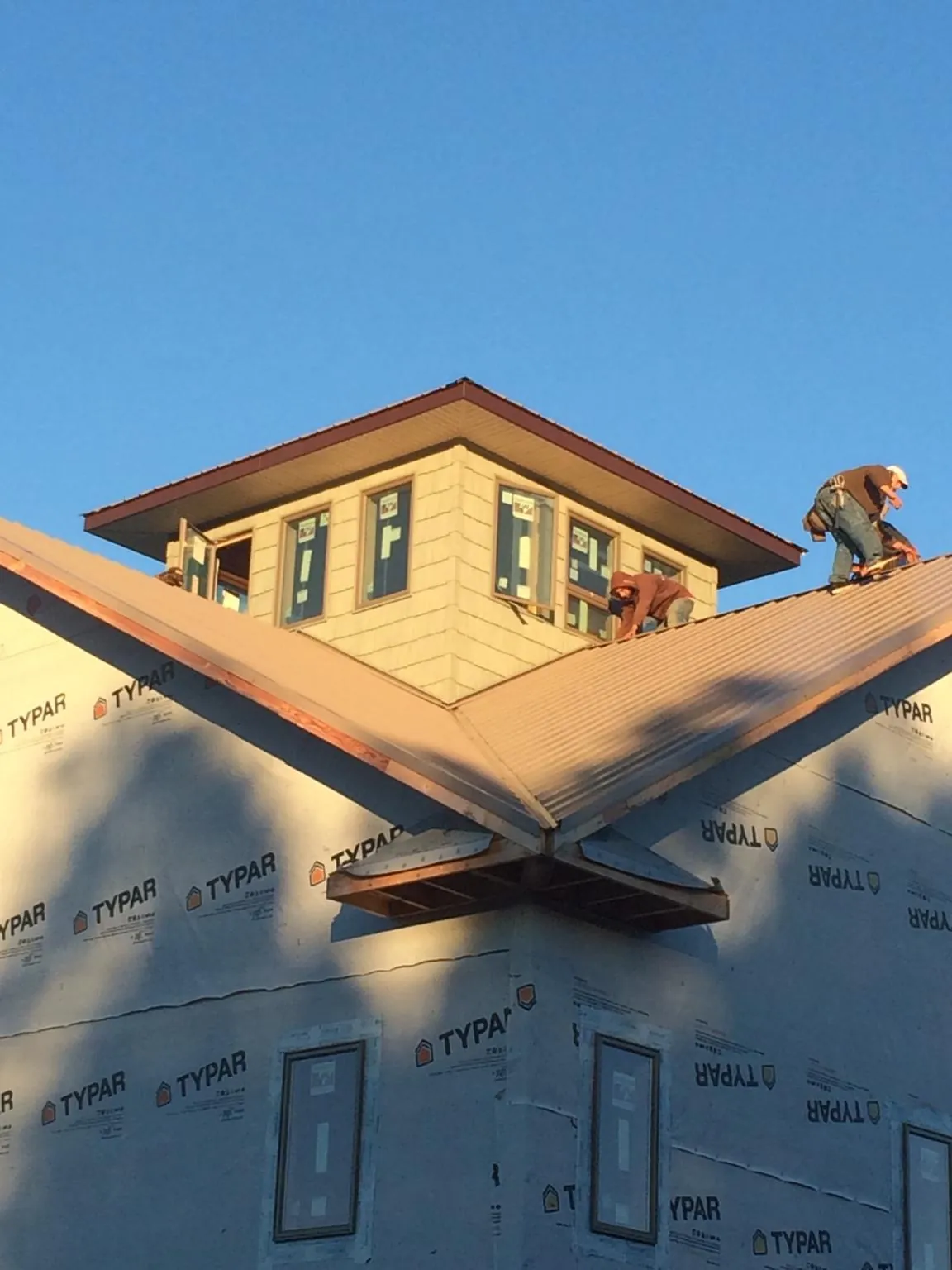 Roofers working around a rooftop cupola on a new metal roof at sunset — Roof Waterproofing in Ogdensburg by Roofing Brothers